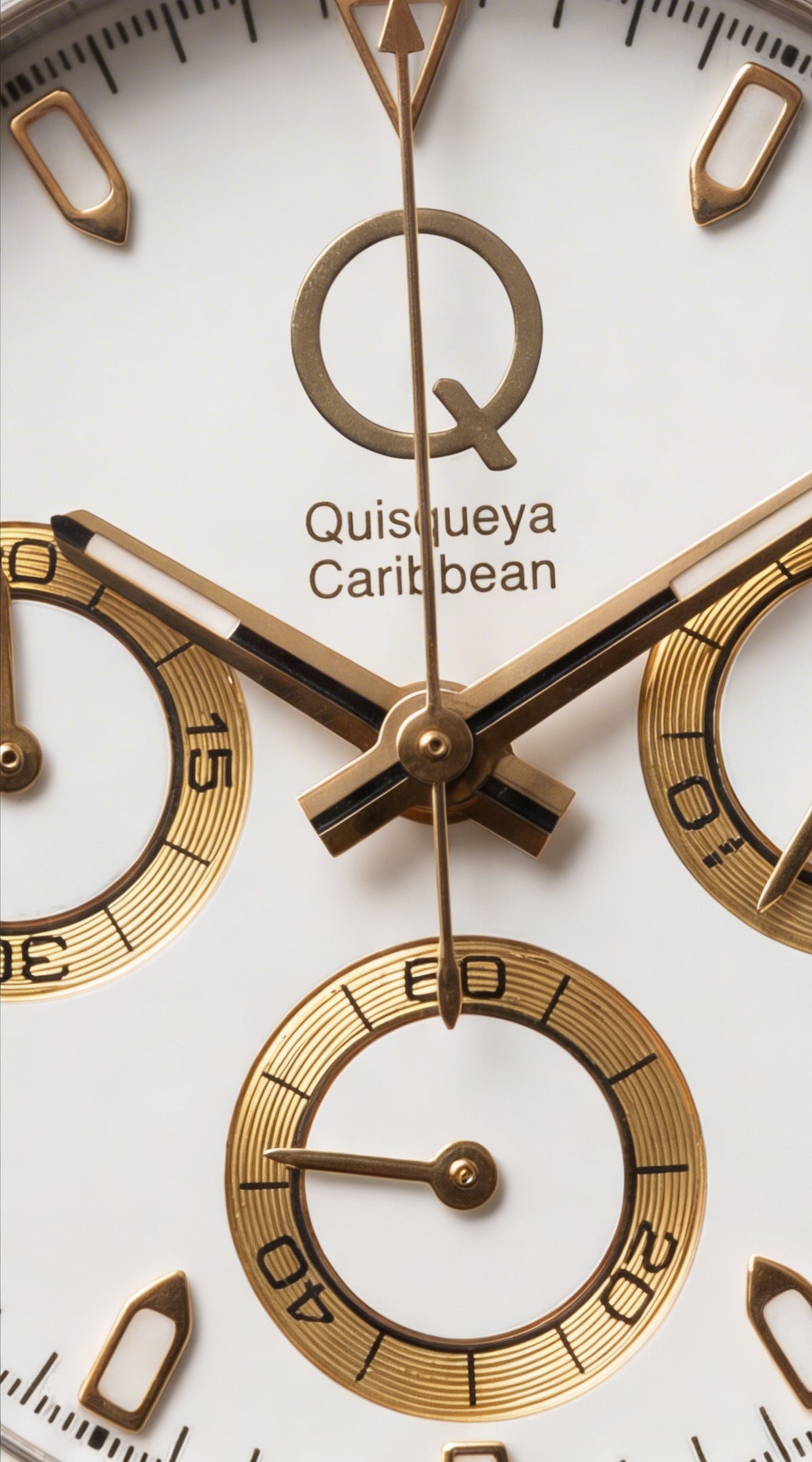 Close-up of a watch dial with gold-tone hands, gold subdials, and the text 'Quisqueya Caribbean' on a white face.